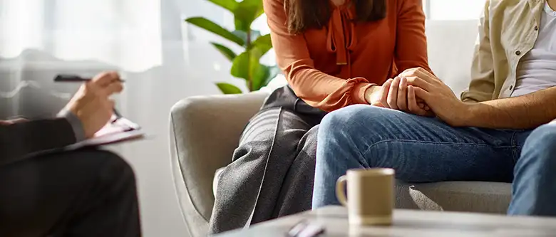 Cropped photo closeup married couple holding hands family therapy psychologist counseling.