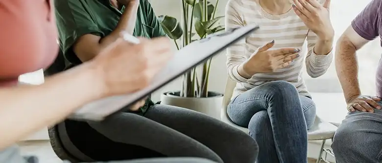 woman taking notes while patients talk